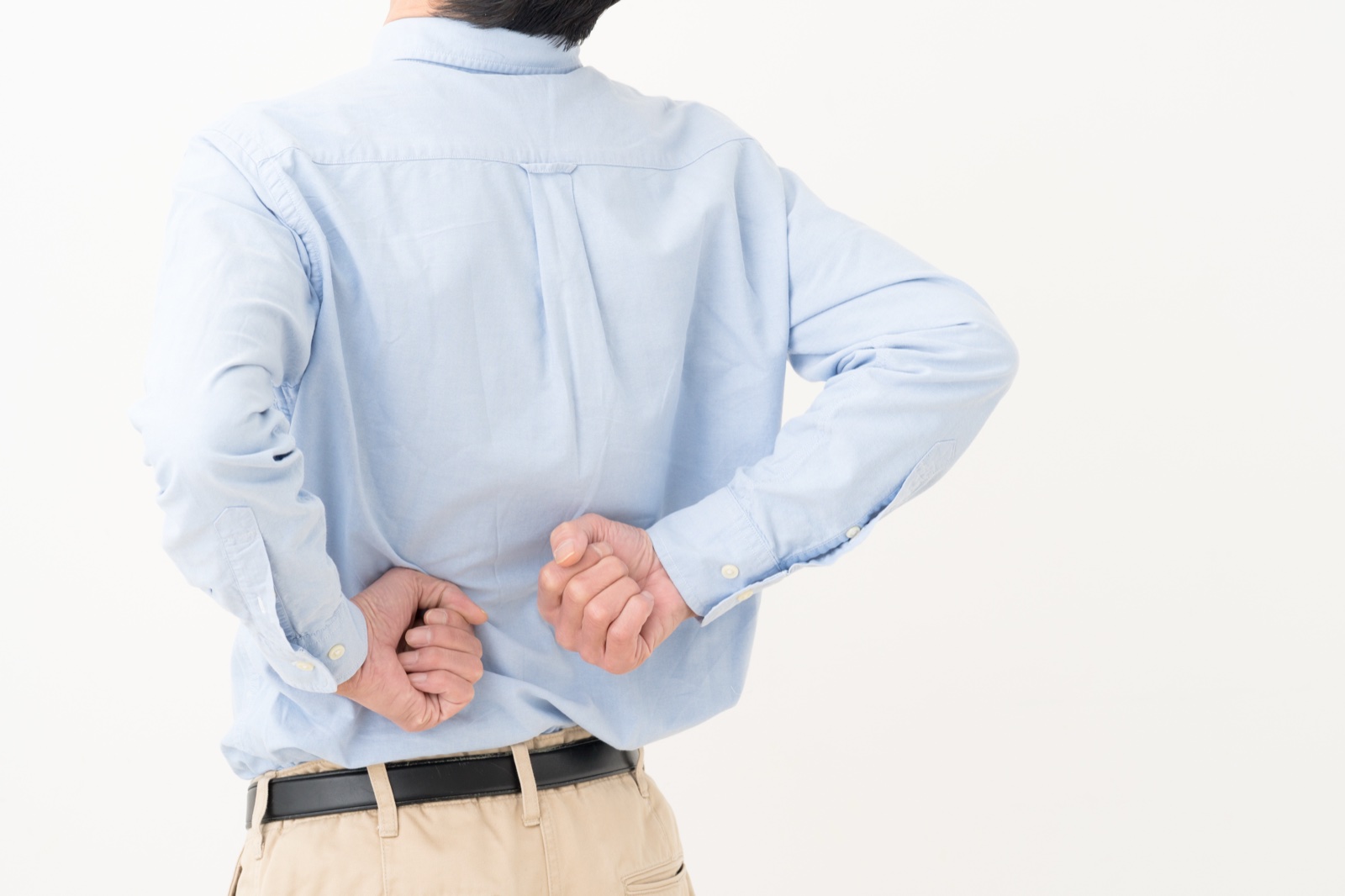 背中の下のほうに両手のこぶしを当てる男性の後ろ姿
