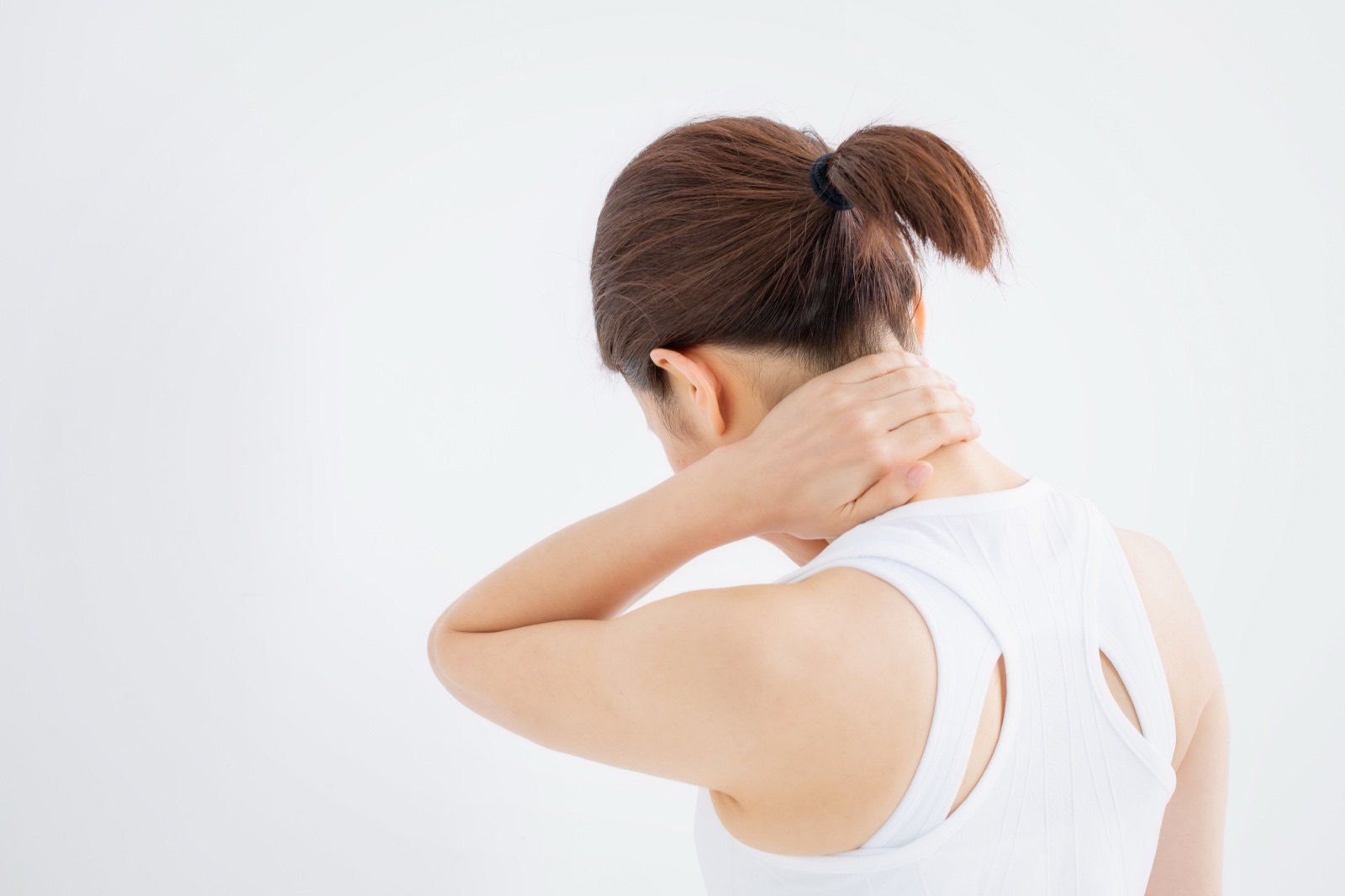 首の付け根に手を当てる白いノースリーブの女性の後ろ姿